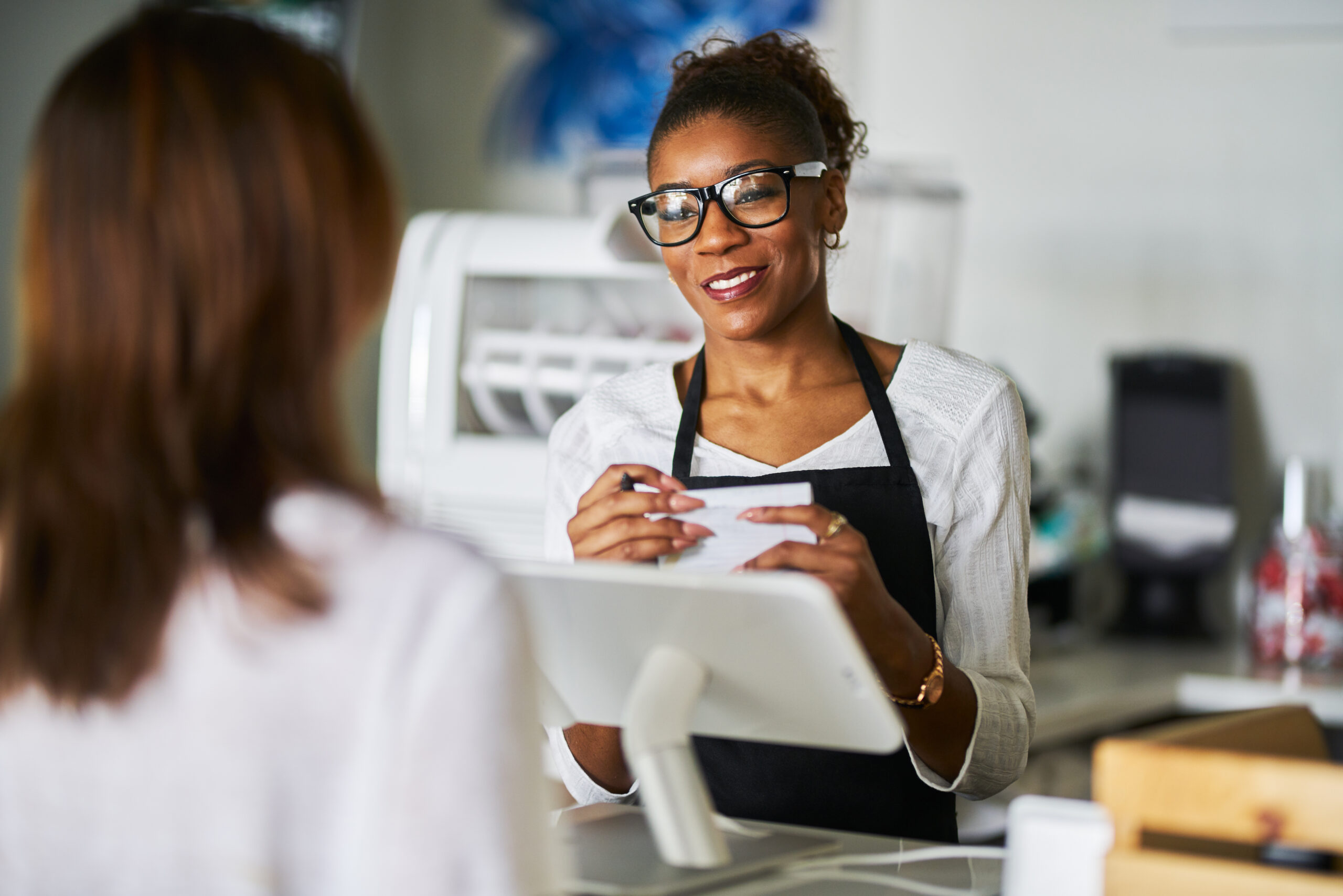 friendly african american waitress taking order on notepad from